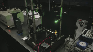 Neuartige Lichtquelle im Labor: Das einfarbige Leuchten (Mitte unten)  wird von einer Schicht mit fluoreszierenden Farbstoffmolekülen und absorbierenden Nanoteilchen erzeugt. 