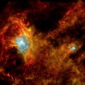 Entstehende Sterne im Sternbild Adler, umgeben vom Staub der dunklen Wolke, der hier orangerot zu sehen ist. Das Bild, aufgenommen vom Weltraumteleskop Herschel im fernen Infrarotbereich. Die beiden hellen Flecken sind Regionen, in welchen große neue Sterne gasförmigen Wasserstoff zum Leuchten bringt.